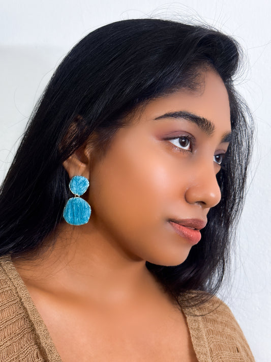 Dangle sea blue statement earrings with layered circular pattern styled as statement jewel