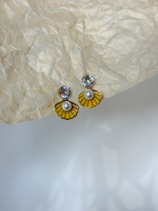 Pair of earrings with yellow and gold floral designs on a textured beige surface.