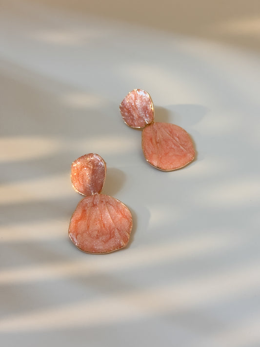 Dangle peach statement earrings with layered circular pattern styled as statement jewel