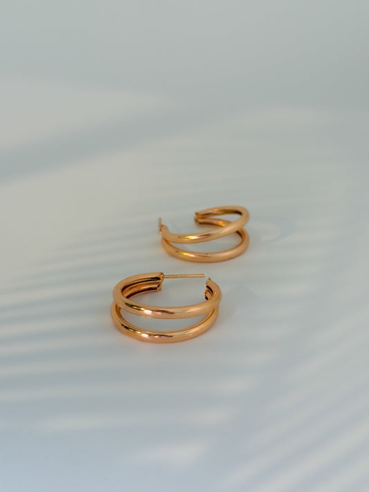 Rose gold hoop earrings on a light gray background