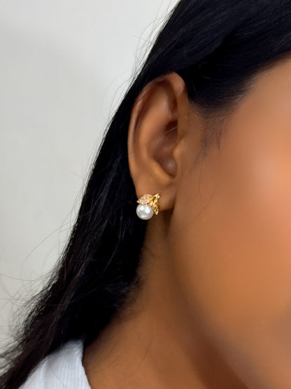 Close-up of an ear wearing a pearl earring with gold earring in a minimal style
