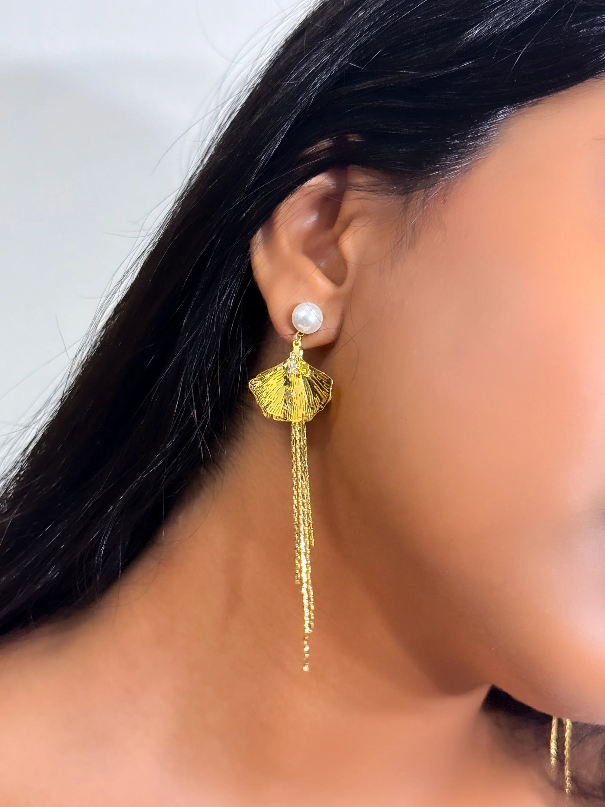 Gold tassel earring with pearl detail worn in a dusky skintone